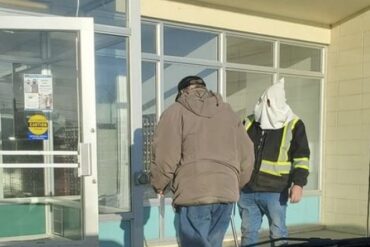 Un homme portant une capuche à la KKK devant un bureau de poste