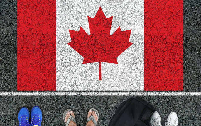 Un drapeau canadien dessiné au sol avec trois paires de pieds, en sandales et deux paires de baskets